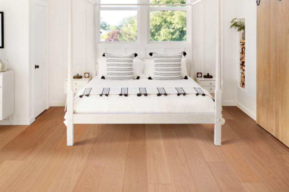 warm toned hardwood flooring in bedroom with white bedroom decor.